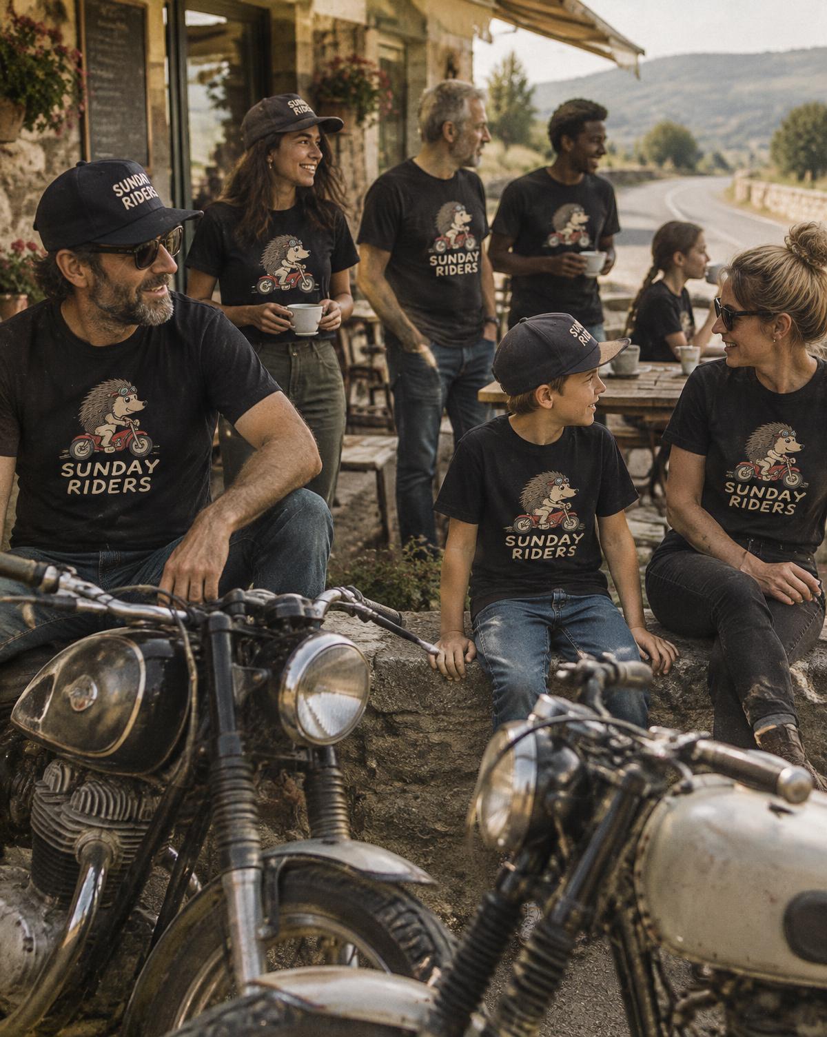 Riders and a kid in black Sunday Riders tees and caps gather by old motorbikes outside a roadside cafe.