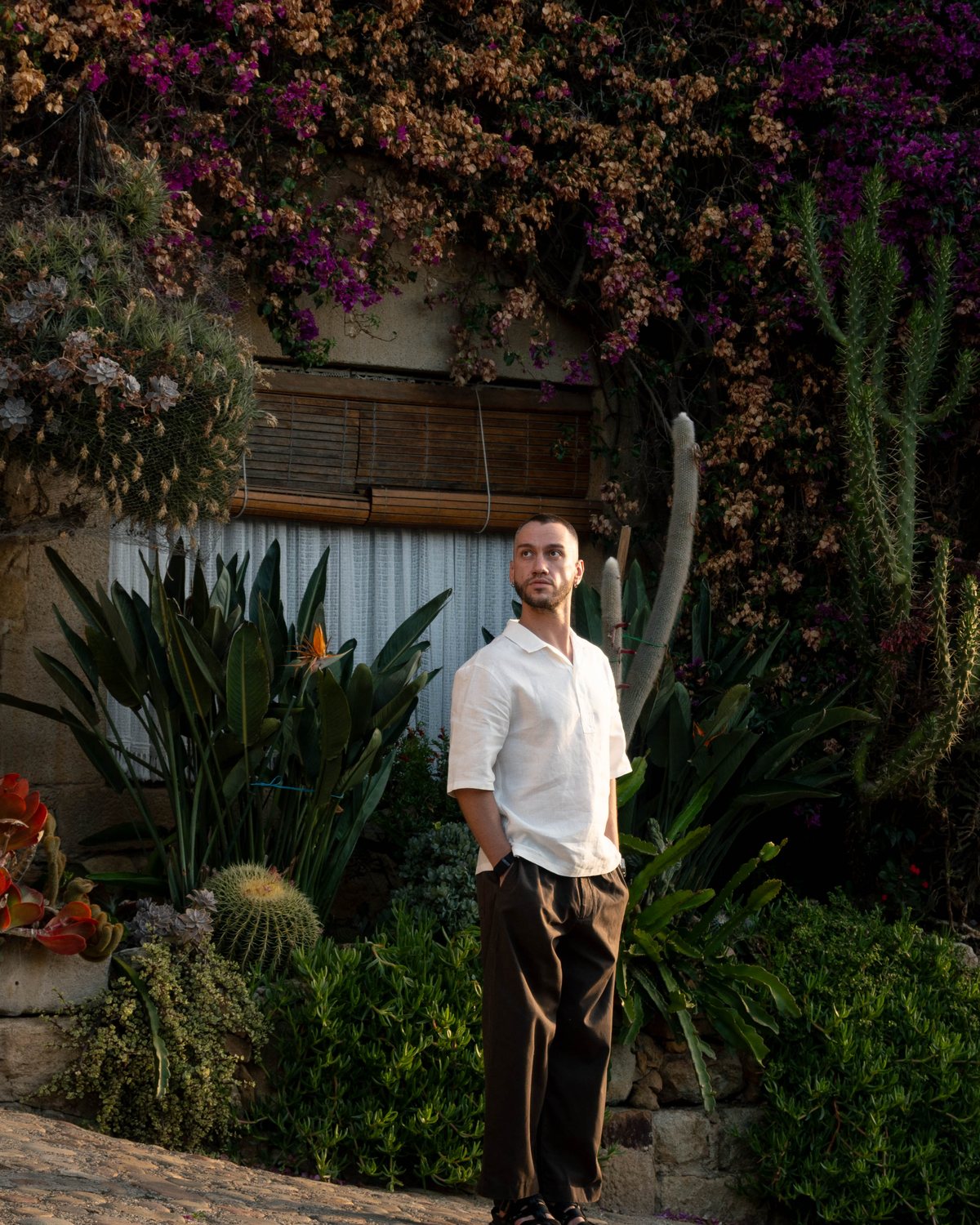 Dmytro Grama, founder of Wooray, in a white linen shirt in front of a bougainvillea wall in Girona