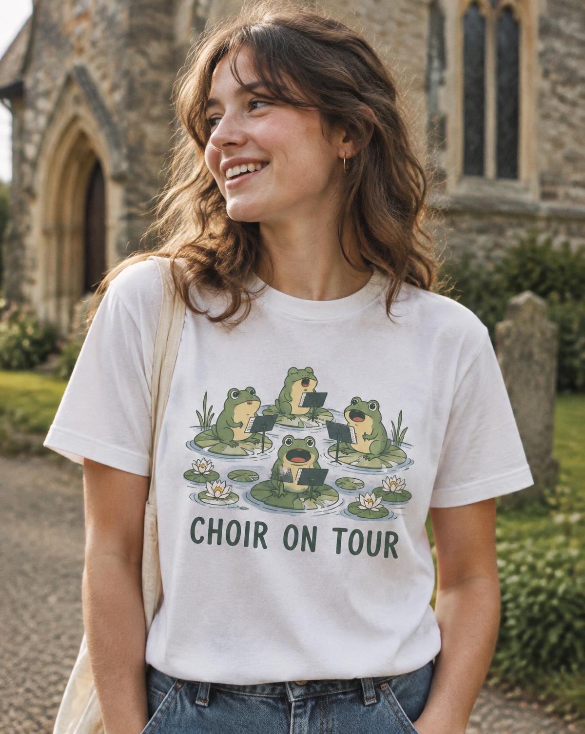 Smiling woman in a white Choir On Tour tee with green singing frogs outside an old stone church.
