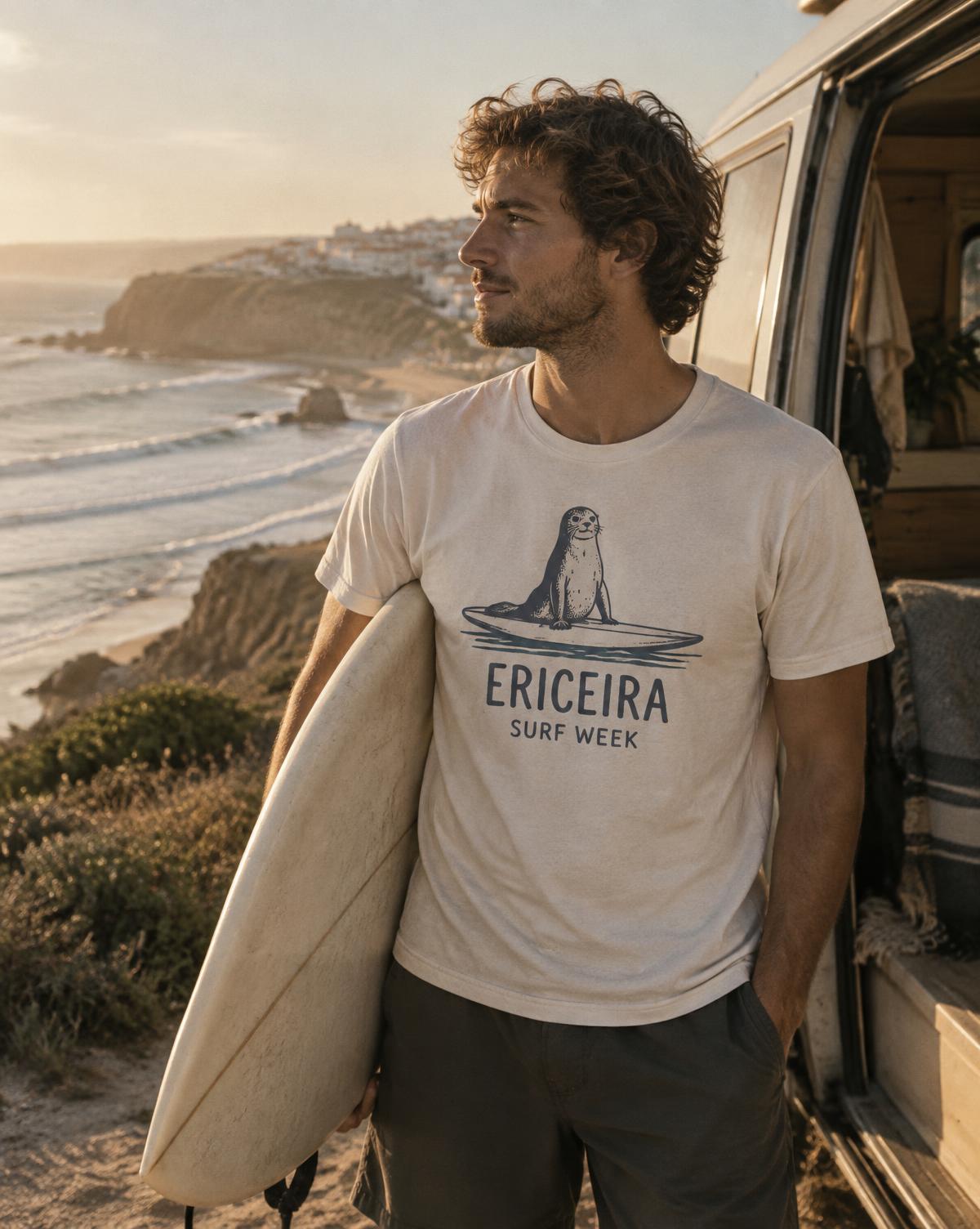 Surfer in a cream Ericeira Surf Week tee with a seal on a board, holding his surfboard by the van.