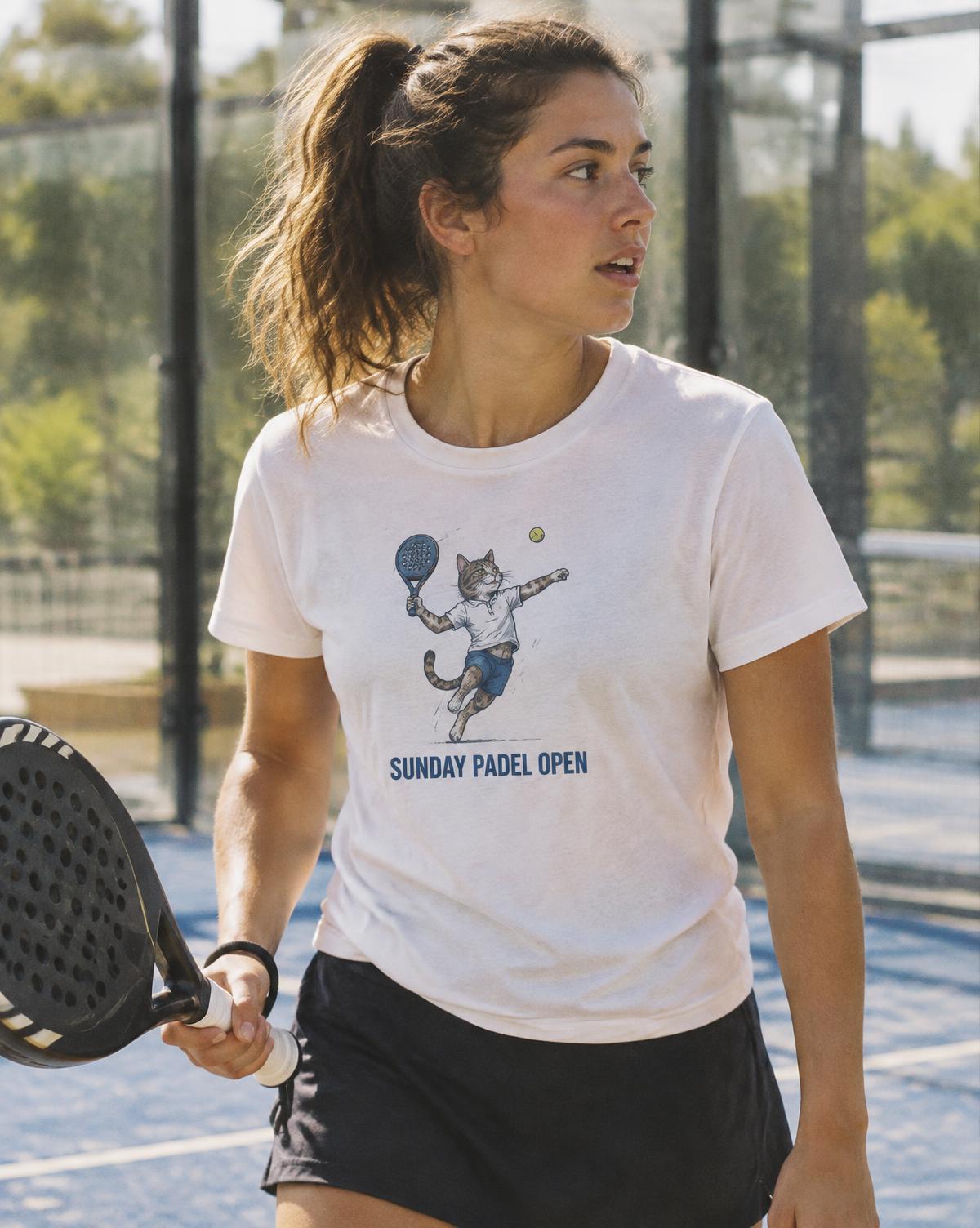 Player in a white Sunday Padel Open tee with a cat mid smash, holding her racket on a blue court.