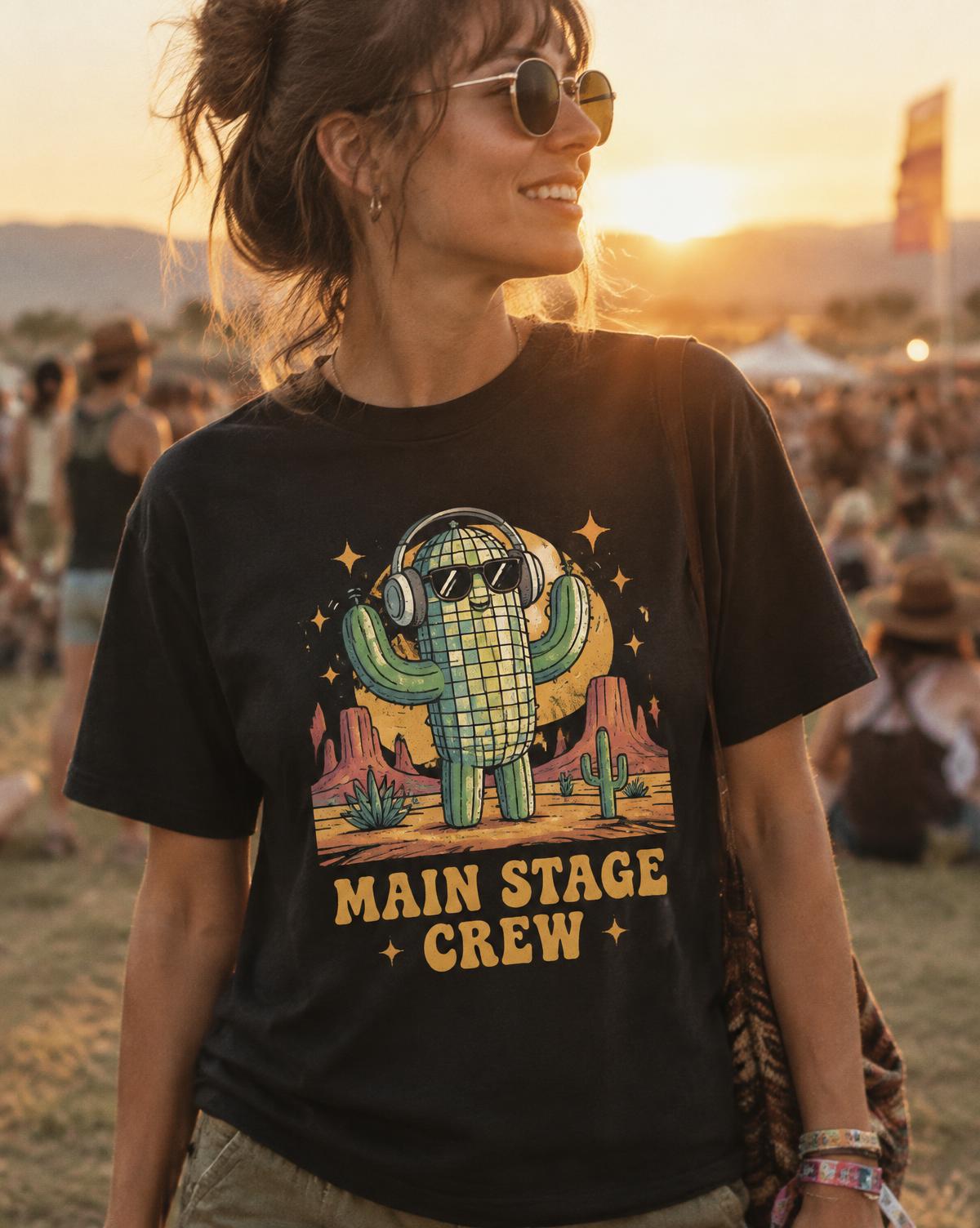 Woman in a black Main Stage Crew tee printed with a disco cactus in headphones at a sunset festival.