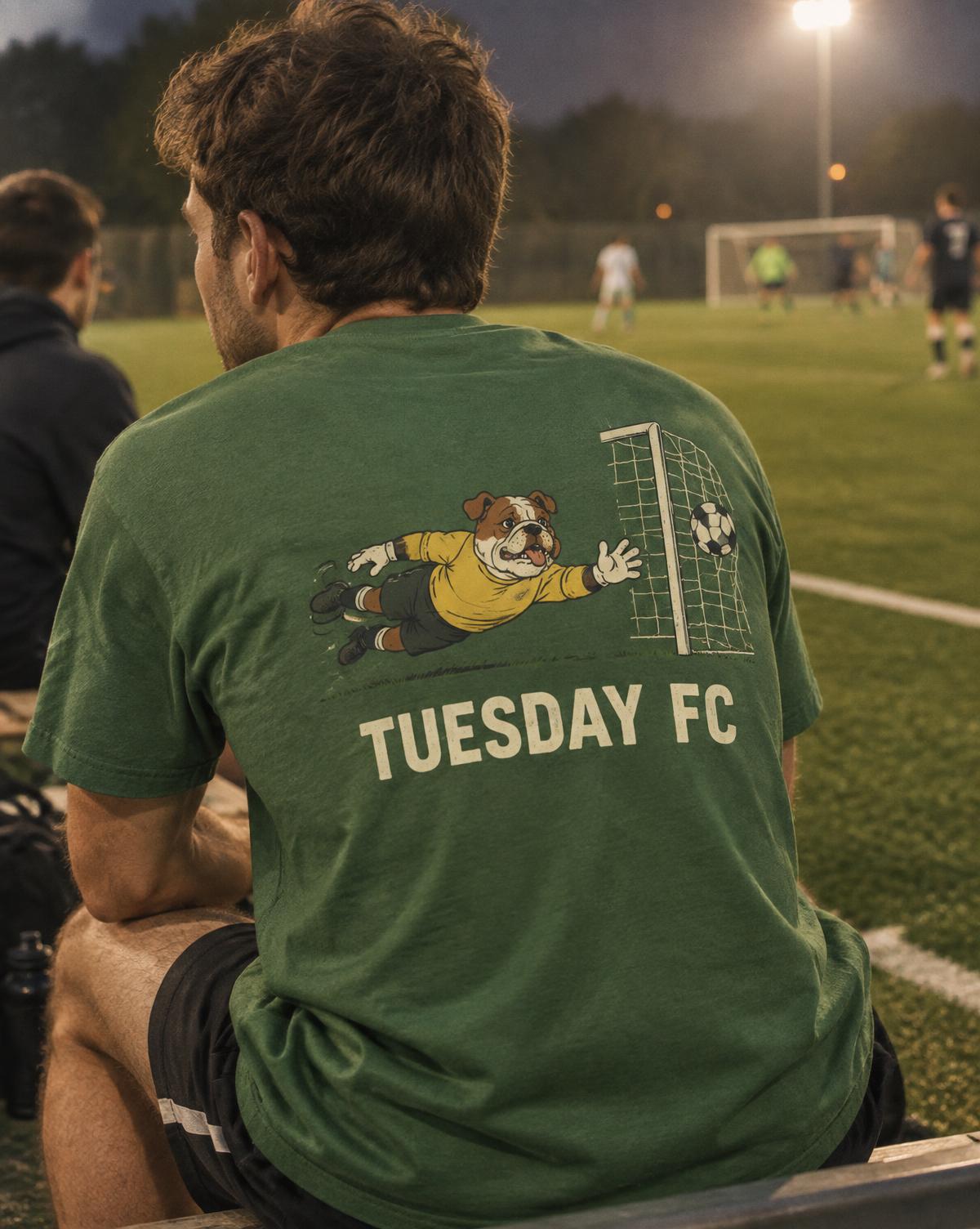 Player on the bench in a green Tuesday FC tee with a bulldog diving the wrong way printed on the back.