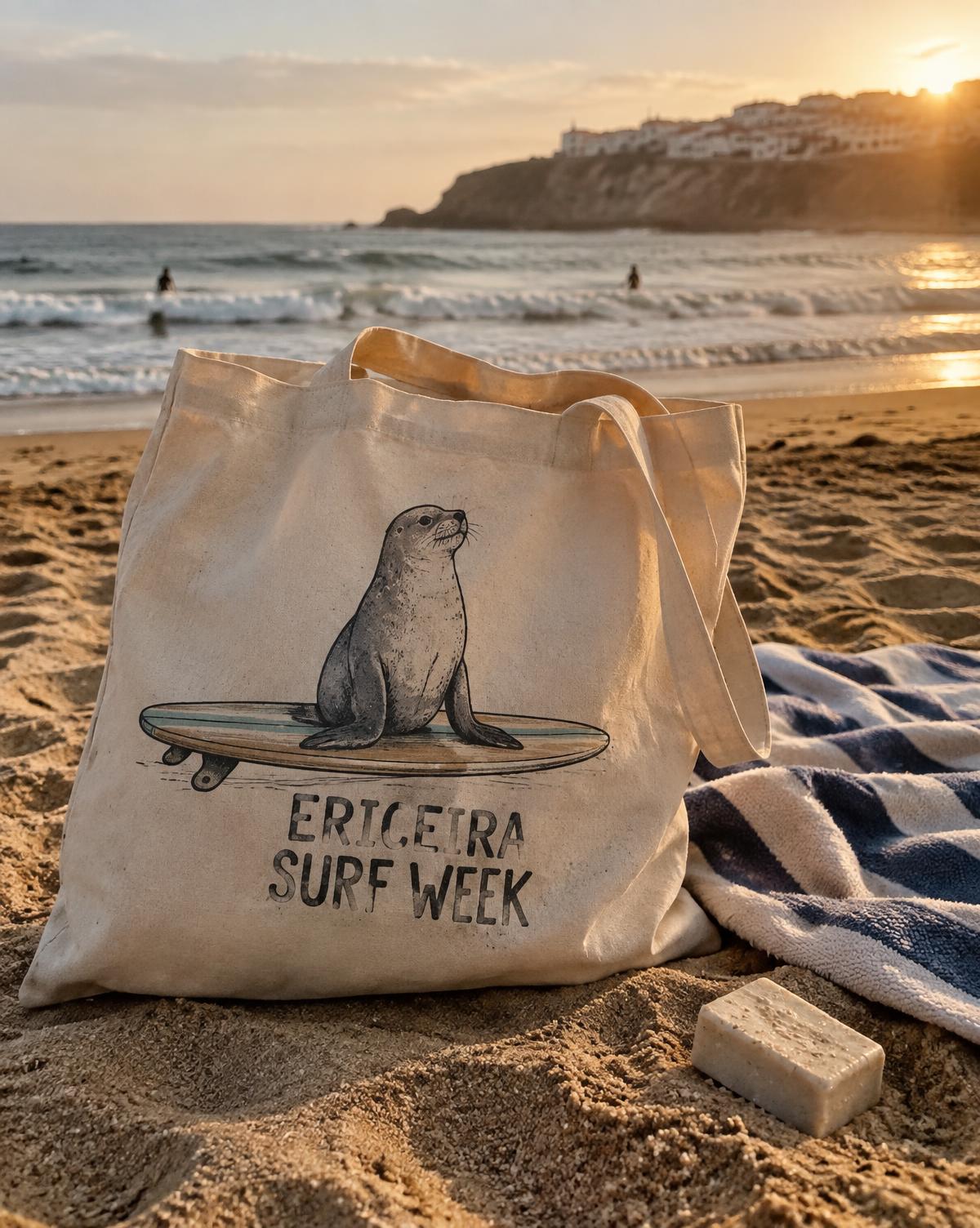 Natural Ericeira Surf Week tote with a seal on a surfboard, lying on the sand by a towel at sunset.