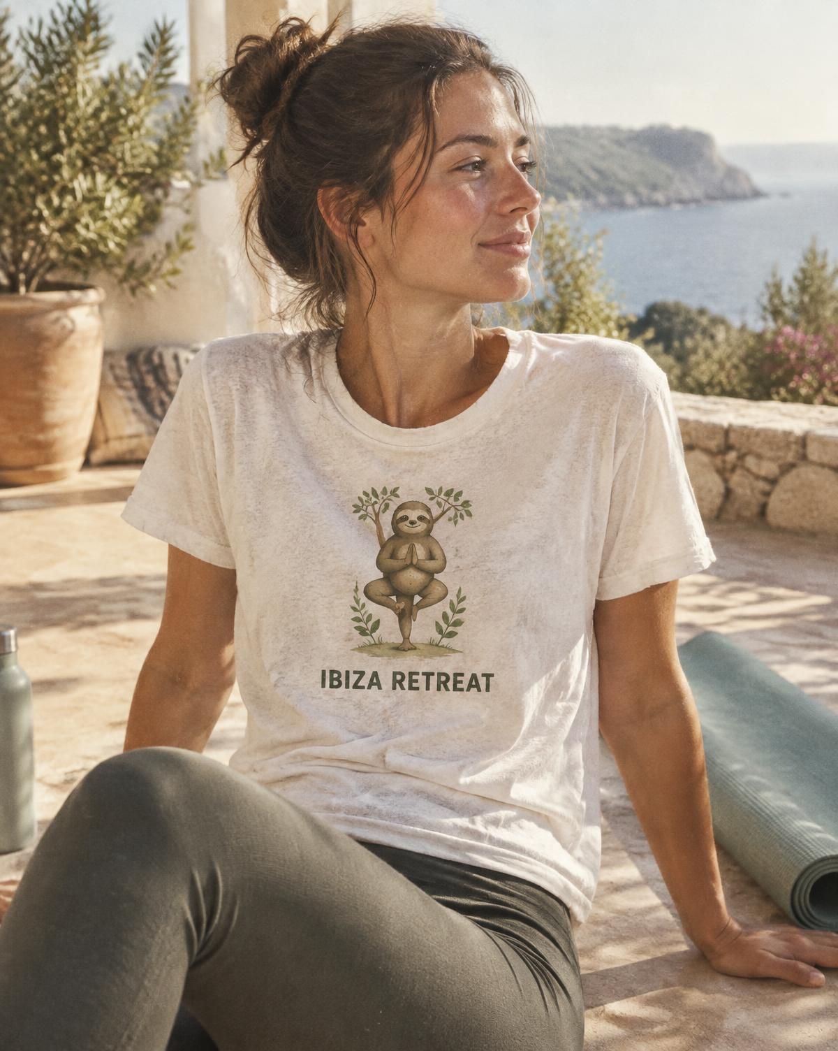 Woman in a cream Ibiza Retreat tee with a sloth in tree pose resting on a terrace above the sea.