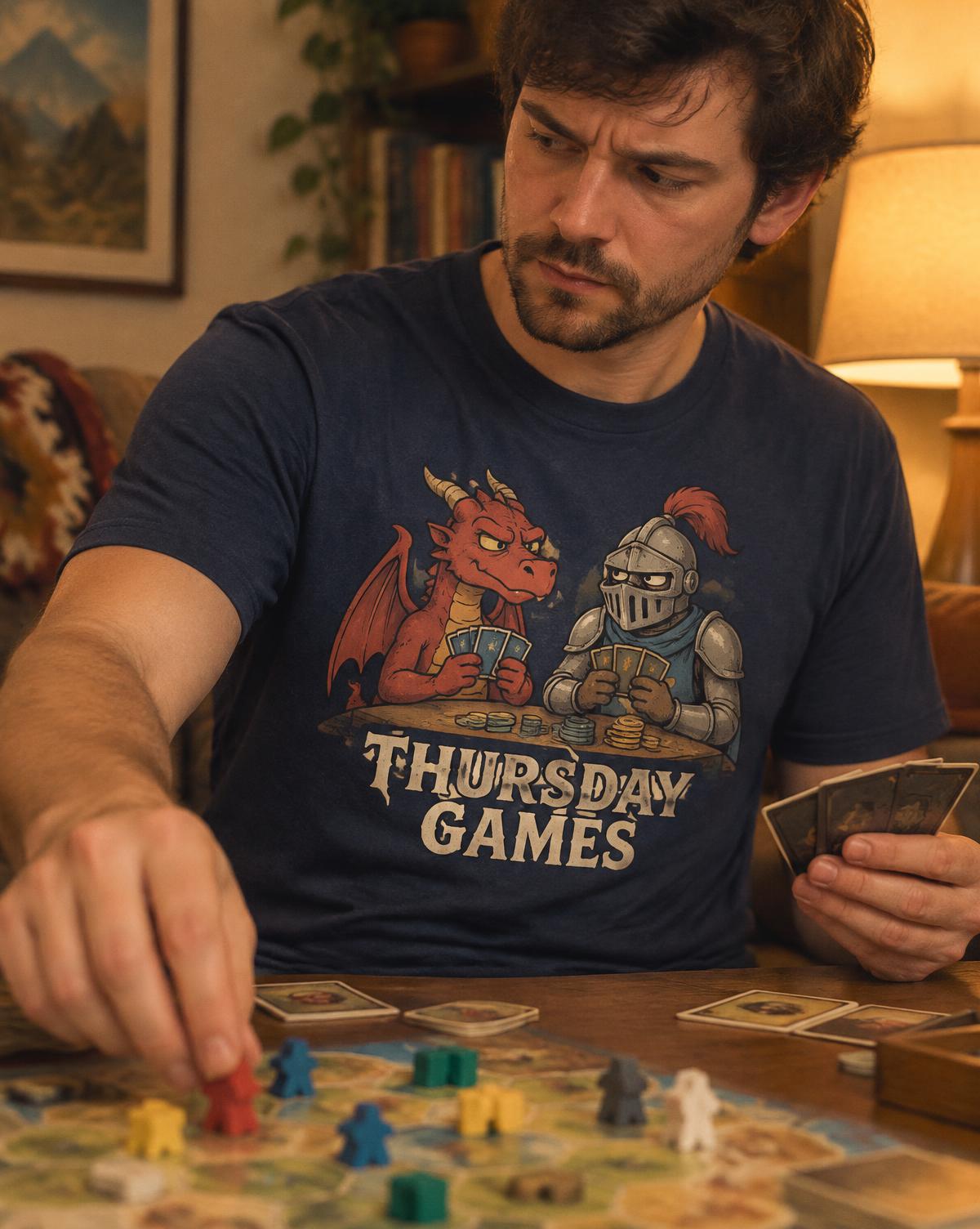 Man in a navy Thursday Games tee with a dragon and knight print moving a piece on a board, looking suspicious.