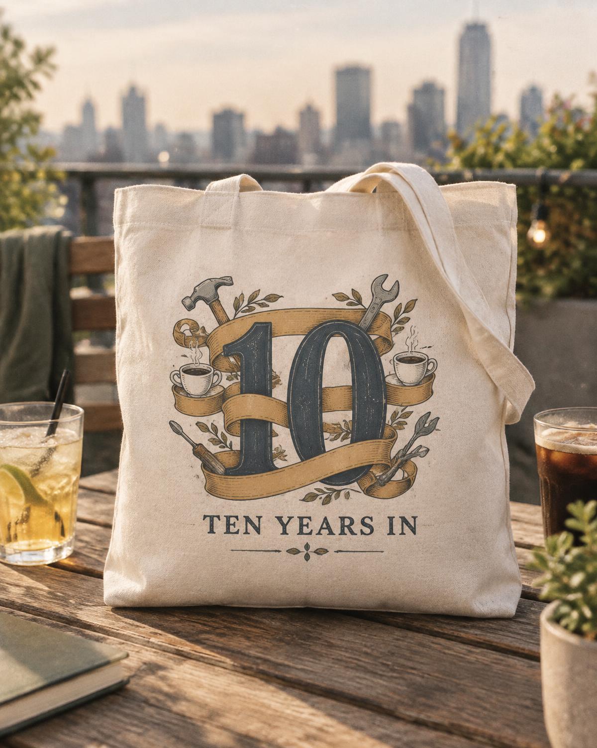 Natural tote with a vintage ribbon around the number 10, tiny tools and cups, and Ten Years In lettering.